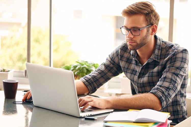 man with glasses working on laptop