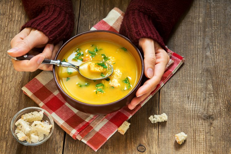 pumpkin soup - woman hands holding bowl of soup