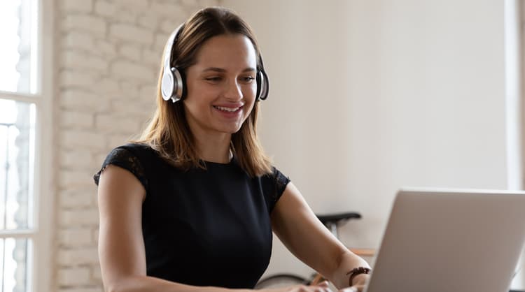 woman using wireless headphones looking at laptop