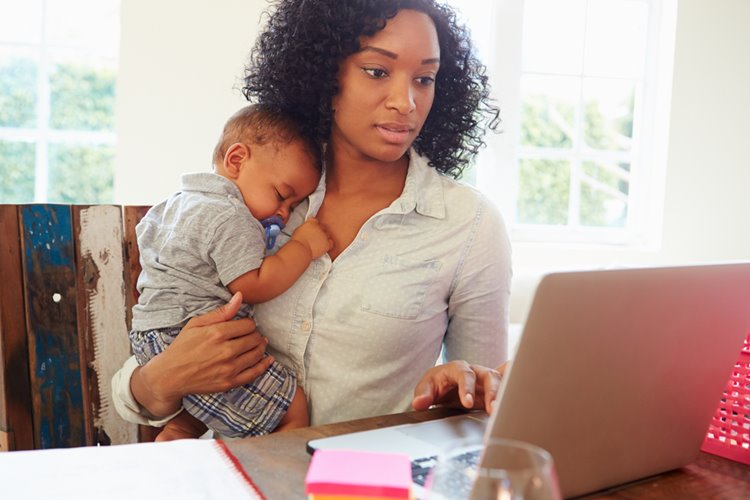 dark-skinned woman working on laptop with baby