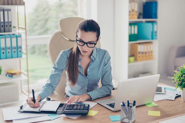 brunette haired woman with glasses working in home office