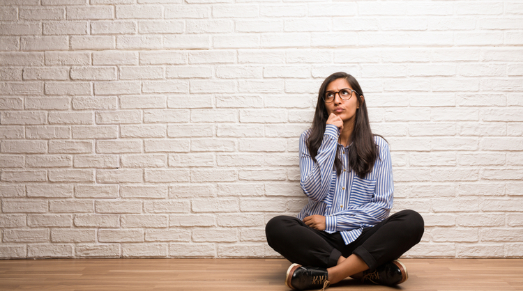 unsure indian woman against brick wall