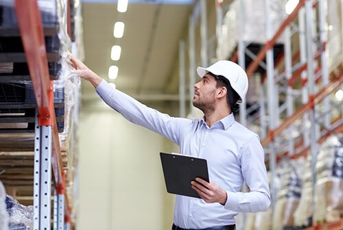 man with helmet doing checks around the warehouse