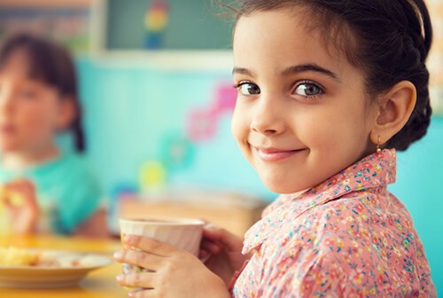 little girl smiling with cup in hand