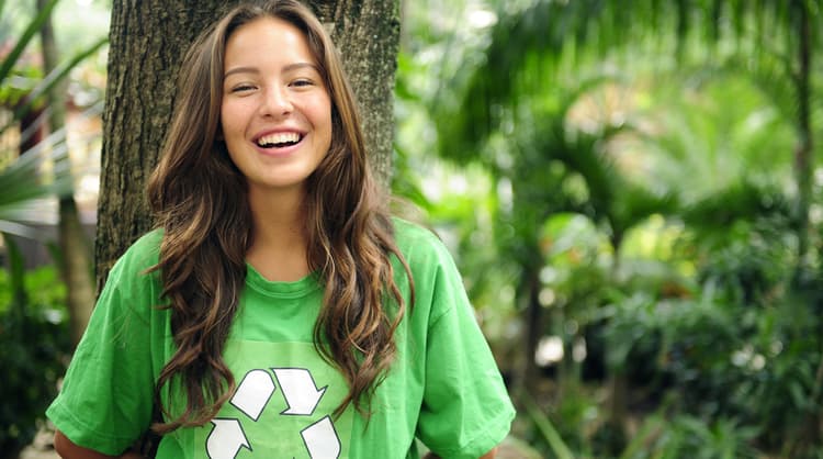 young teenage girl smiling for photo, wearing t-shirt with recycling symbol