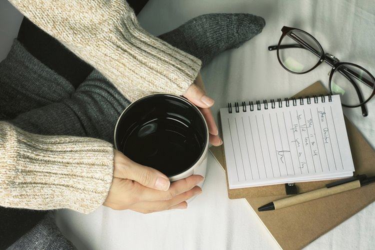 woman wearing warm sweater and studying in bed